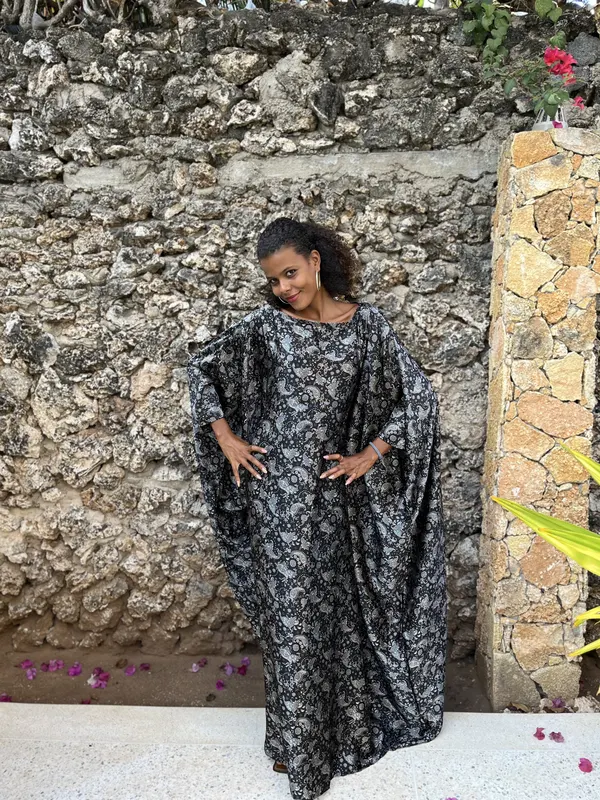 Model in the Jiwe kaftan against a coral stone wall